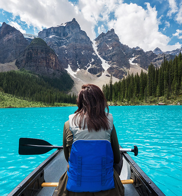 Woman canoeing looking up at mountains