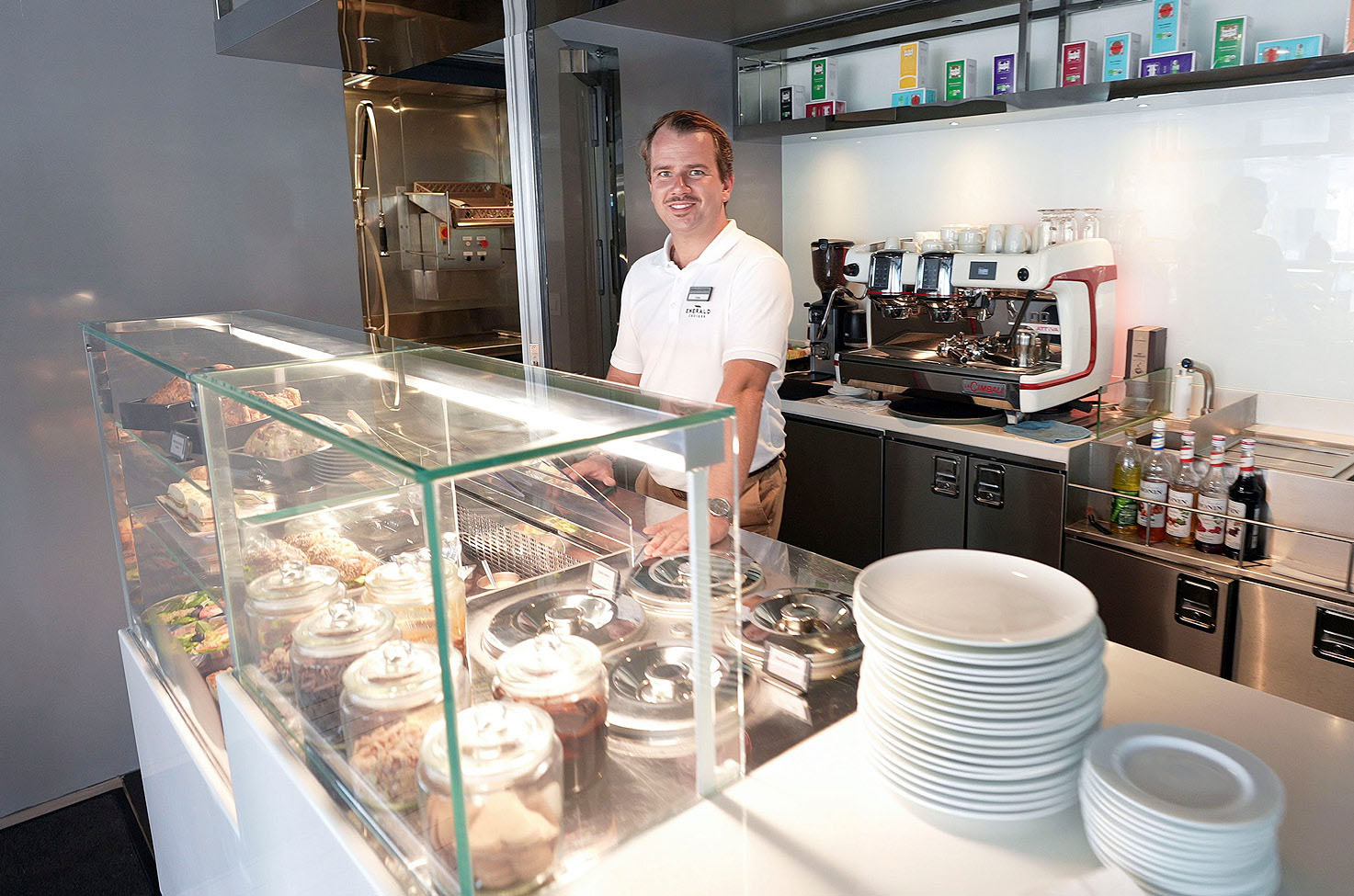 Server standing behind a clean counter, next to a stack of clean white plates