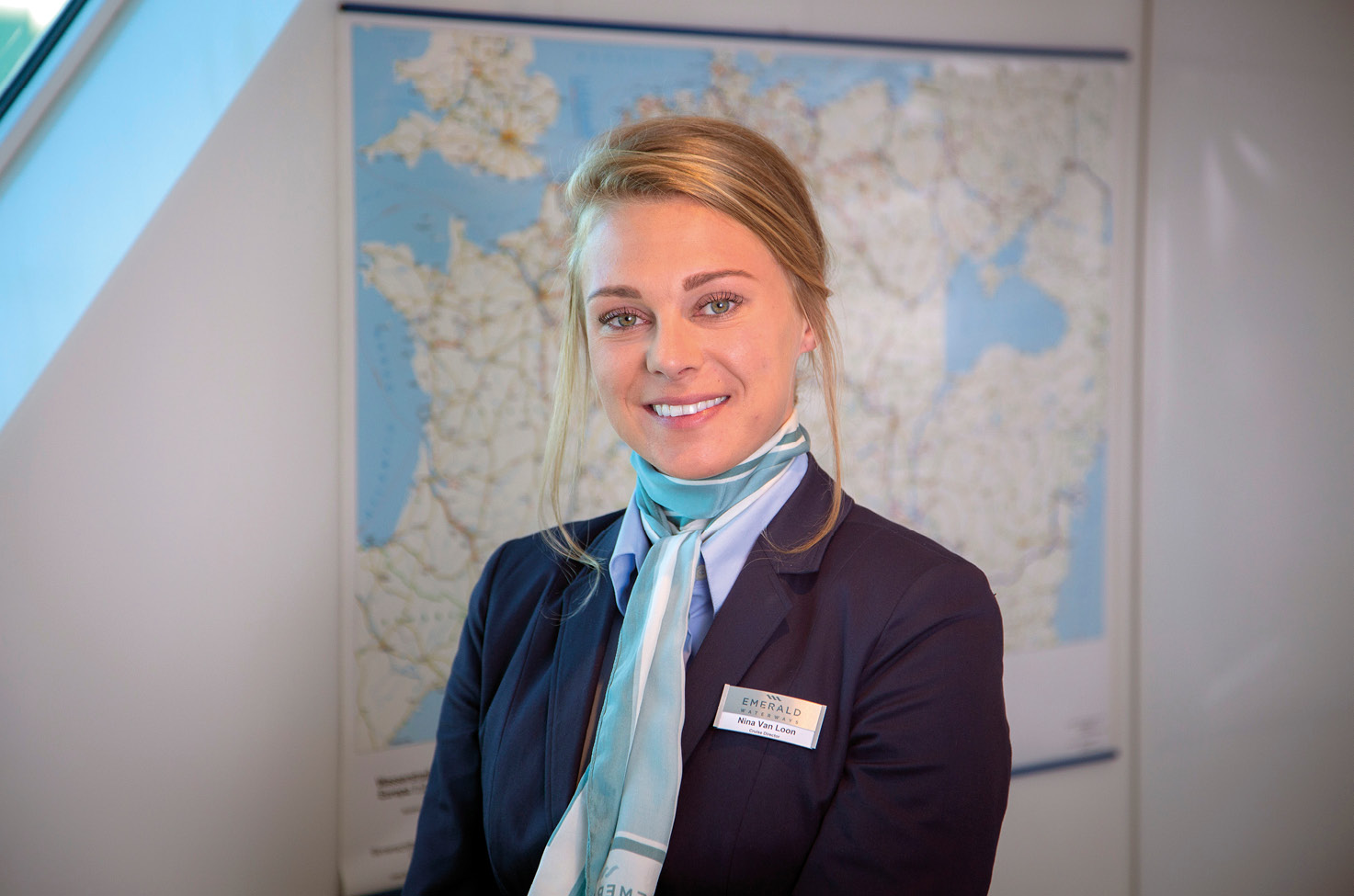 A smiling crew member on board an Emerald Cruises river ship stood in front of a map